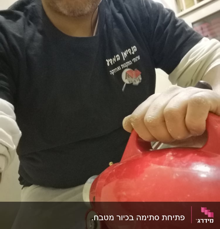 אדם מחזיק מכשיר אינסטלציה אדום